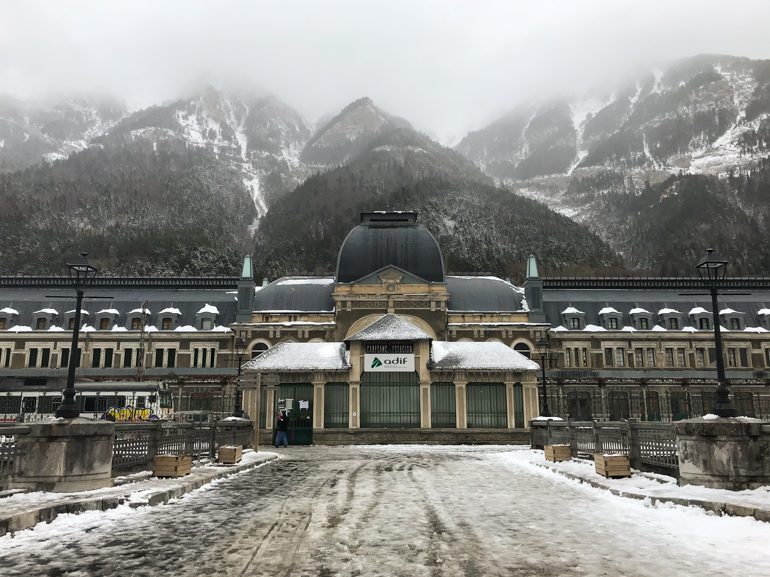 fachada principal de la estación de canfranc con las montañas nevadas al fondo